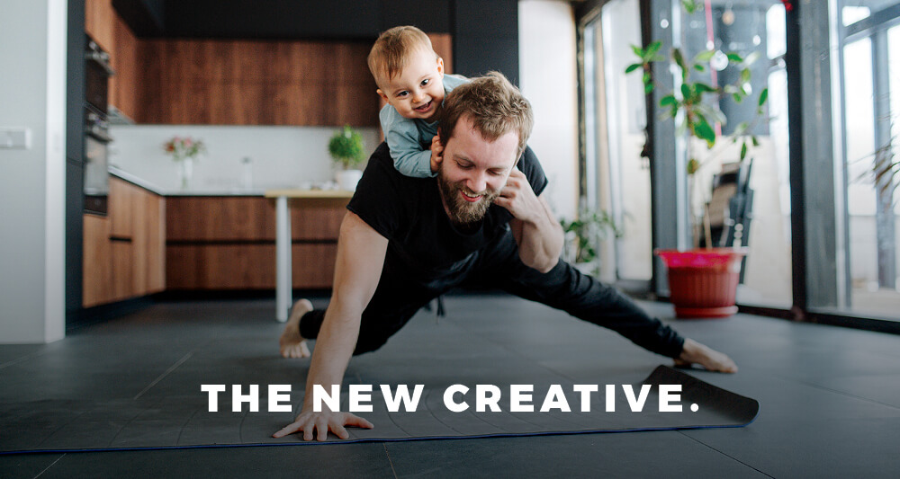 Father attempting to stretch or exercise at home, with his young baby on his back, both smiling..